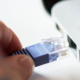 Hand plugging Ethernet network cable into laptop RJ45 port for internet connection